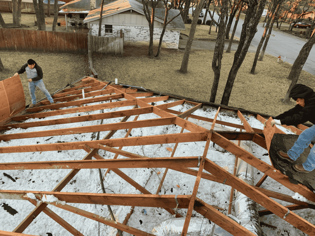 Roofers removing plywood panels during a residential roof repair project in Dallas, TX