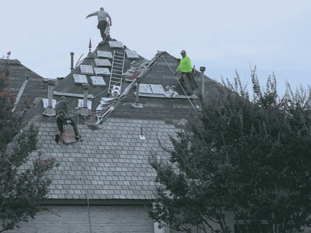 Roofers installing shingles on a residential roof with safety gear and professional tools in Dallas, TX.